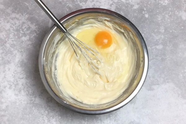 Gradually add the eggs to the cream cheese mixture, stirring thoroughly after each addition. It's best to use a whisk or spatula for this. Important note: do not use a mixer at this stage! Take your time and mix gently to avoid incorporating too much air into the batter, which could lead to a runny mixture. (Keep in mind that if the cheesecake batter is overly aerated, the cheesecake may rise and crack during baking).

