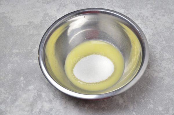 Pour the melted butter into a mixing bowl and add the sugar. Whisk the mixture until well combined. The warmth of the butter will aid in melting the sugar.

