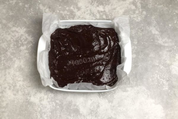 Take a baking dish, cover it with baking paper. To make the paper fit better, first fold it. Pour the dough into the mold and spread it evenly with a spatula.

