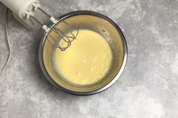 While the chocolate is cooling, beat the eggs with powdered sugar in a separate bowl with a mixer until fluffy and light. Wash the eggs in running water with baking soda before use, as there may be harmful bacteria on their surface.


