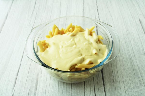 In a suitable container, combine the cooked pasta with the cheese sauce and mix well.

