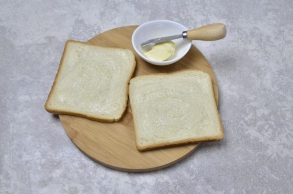 Classic cheese sandwiches often use toast bread, like mine. However, you can use any bread, from a loaf to white or wholemeal varieties; although, I haven't tested this recipe with rye bread. Ensure the butter is softened by removing it from the refrigerator in advance. Use high-quality butter without vegetable fats. Spread butter on one side of both slices of bread.

